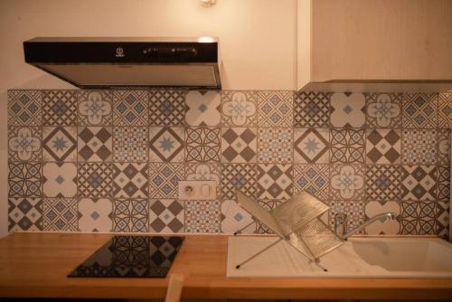 eine Küche mit einem Waschbecken und einer gefliesten Wand in der Unterkunft Chez Moltess in Seignosse