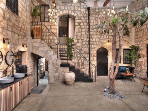 a stone building with a staircase and a tree at אבני החושן - סוויטות יוקרה בצפת העתיקה - Avnei Hachoshen - Luxury Suites in the Old City in Safed