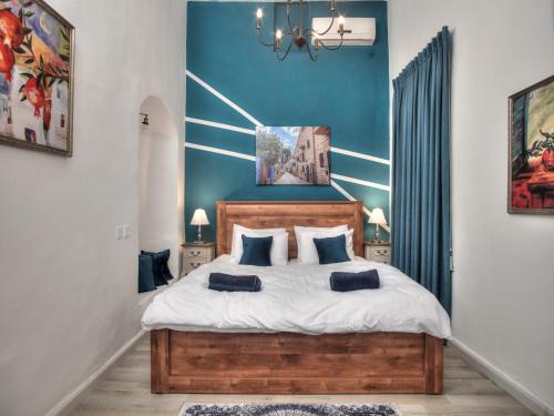 a bedroom with a large bed with blue walls at אבני החושן - סוויטות יוקרה בצפת העתיקה - Avnei Hachoshen - Luxury Suites in the Old City in Safed