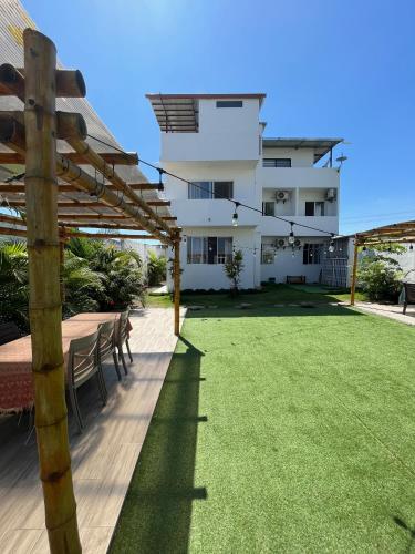 a backyard with a wooden pergola and a lawn at Mare S&M Casa Hostal in Manta