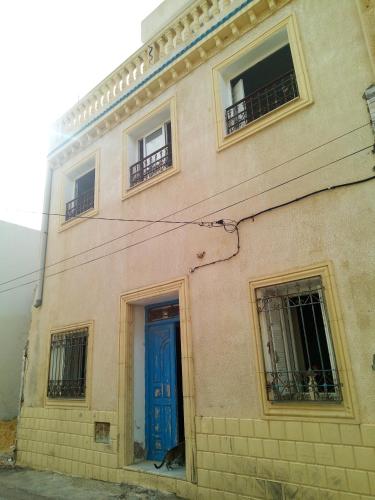 un edificio con una puerta y ventanas azules en Chez Karim, en Mahdia