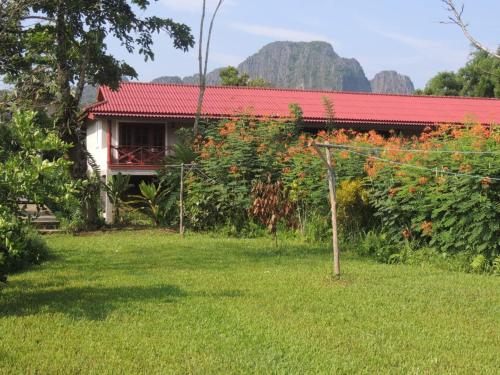 une maison avec un toit rouge à côté d'une cour dans l'établissement Maylyn Guesthouse, à Vang Vieng