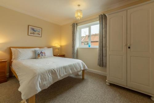 Avocet Apartment في ويلز نكست ذا سي: غرفة نوم صغيرة بها سرير ونافذة
