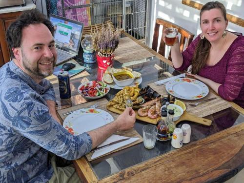 a man and a woman sitting at a table with food at Sunshine Court in St Paul's Bay