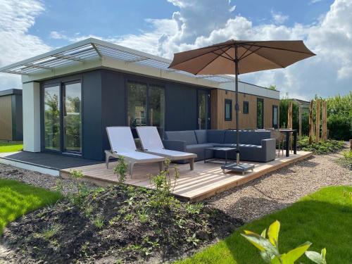 Cette maison dispose d'une terrasse avec un parasol. dans l'établissement Zonneweelde, Vakantie aan Zee, à Nieuwvliet-Bad