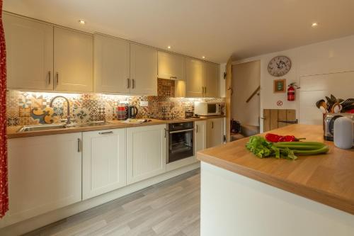 a kitchen with white cabinets and a wooden counter top at Hollyhocks in Docking