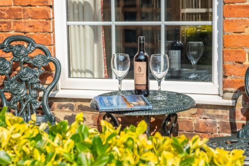 a bottle of wine and two glasses on a table at Hollyhocks in Docking