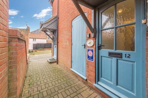 a brick building with a blue door on it at Curlew Apartment in Wells next the Sea