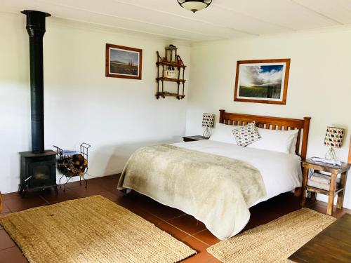a bedroom with a bed and a wood stove at Hermitage Huisies in Swellendam