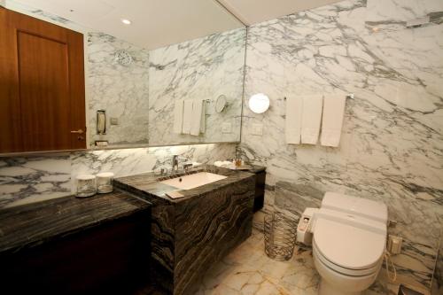 a bathroom with a toilet and a sink and a mirror at Lotte Hotel Busan in Busan