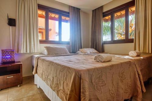 a bedroom with two beds and two windows at Pipa Beleza Ap aconchegante in Pipa