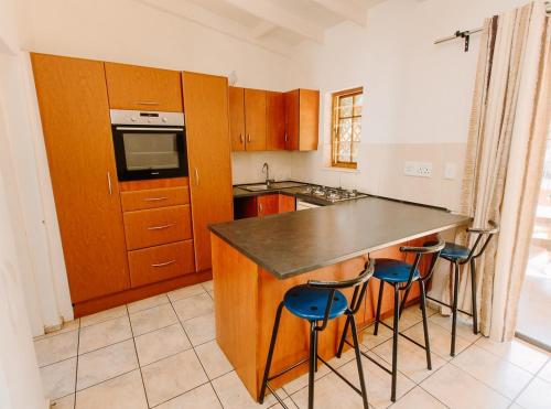 a kitchen with wooden cabinets and a counter with stools at Golden Candle Guest House in Roodepoort