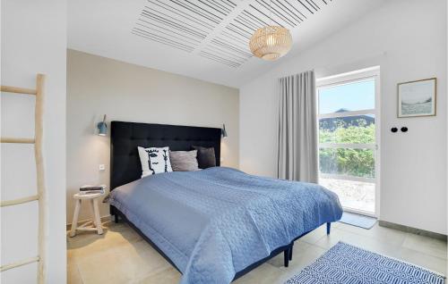 a bedroom with a blue bed and a window at Amazing Home In Hvide Sande With Outdoor Swimming Pool in Hvide Sande
