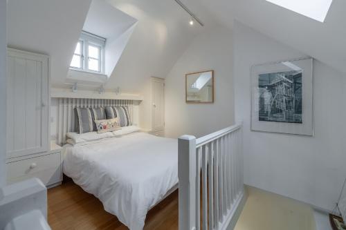 a white bedroom with a bed and a window at Newgate Boathouse in Wells next the Sea