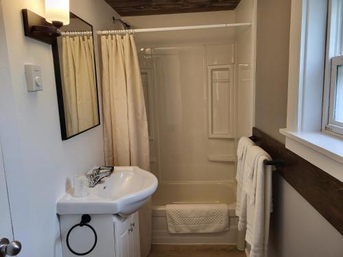 uma casa de banho branca com um lavatório e um chuveiro em Scoodic Motel em Saint Stephen