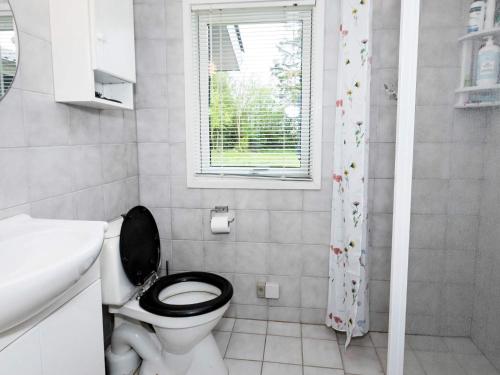 La salle de bains est pourvue de toilettes, d'un lavabo et d'une fenêtre. dans l'établissement Holiday home Vesløs IV, à Øsløs