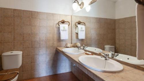 a bathroom with two sinks and a toilet and a mirror at Casa Rural Las Catenas Andújar by Ruralidays in Jaén