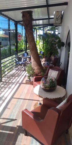 a patio with chairs and a tree in the middle at Pousada Rosa de Saron in Holambra