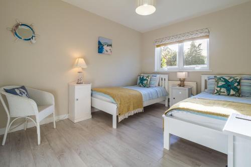 a bedroom with two beds and a chair and a window at Sea Lodge in Brancaster