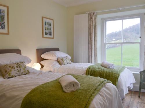 a bedroom with three beds with towels on them at Tyllwyd Farmhouse in Capel Bangor