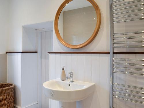 a bathroom with a sink and a mirror on the wall at Tyllwyd Farmhouse in Capel Bangor