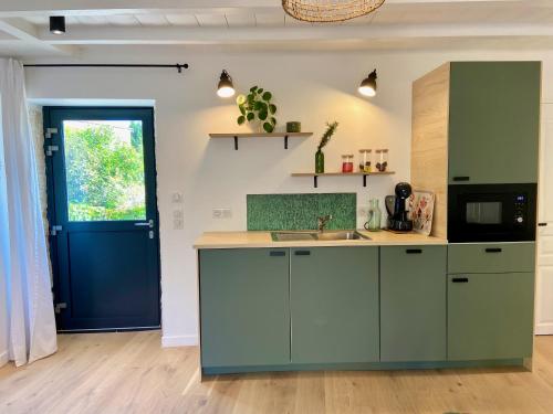 une cuisine avec des placards verts et une porte bleue dans l'établissement La petite Maison Messigny, à Vantoux