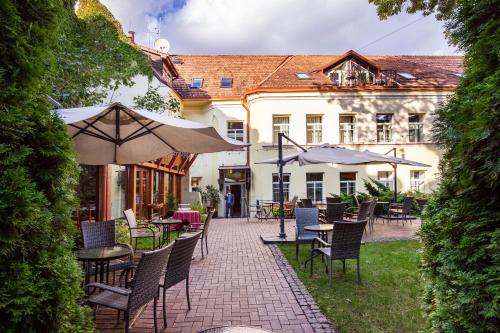 an outdoor patio with chairs and tables and umbrellas at Grotthuss Boutique Hotel Vilnius in Vilnius