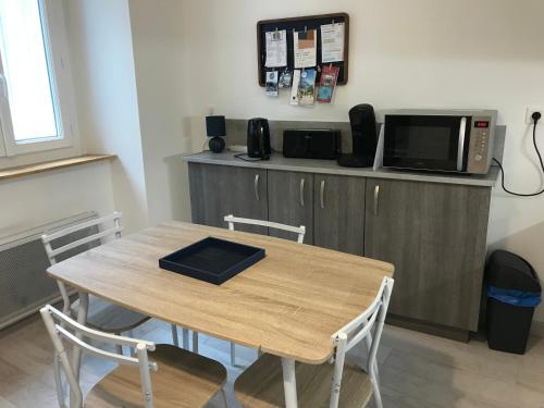 une table avec des chaises et un micro-ondes sur un comptoir dans l'établissement Le gite bleu, à Ax-les-Thermes