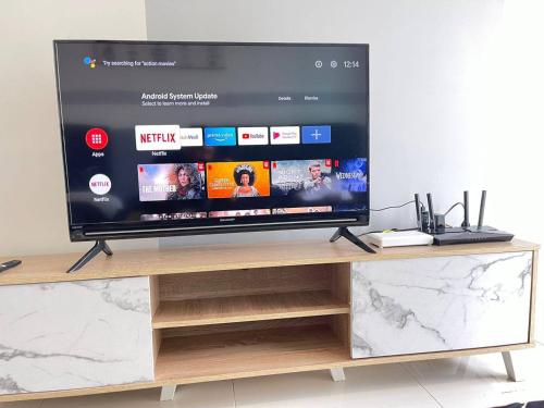 a large flat screen tv sitting on a wooden entertainment center at Teega Suites Seaview by VDO Homestay in Nusajaya