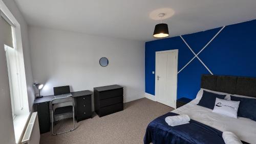 Townhouse in Harwich في هارويتش: غرفة نوم بجدران زرقاء وسرير ومكتب