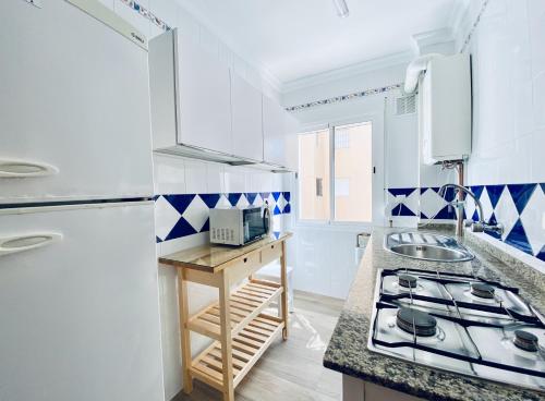 a white kitchen with blue and white tiles at Apartamentos Turísticos Santo Rostro in Chipiona