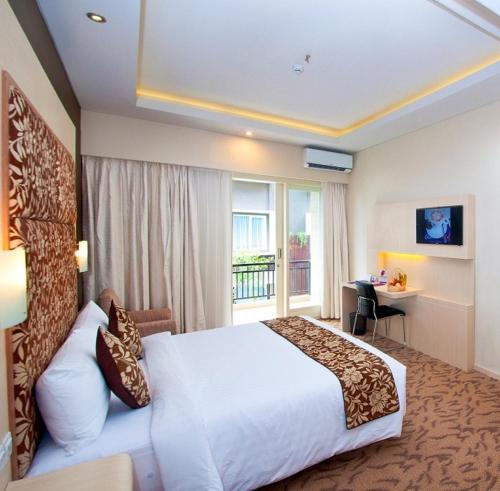 a hotel room with a large bed and a window at Quest San Denpasar by ASTON in Denpasar