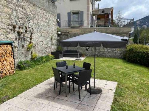 a table and chairs under an umbrella in a yard at Charmant 2,5 pièces avec jardin à 2 pas du lac in Champex