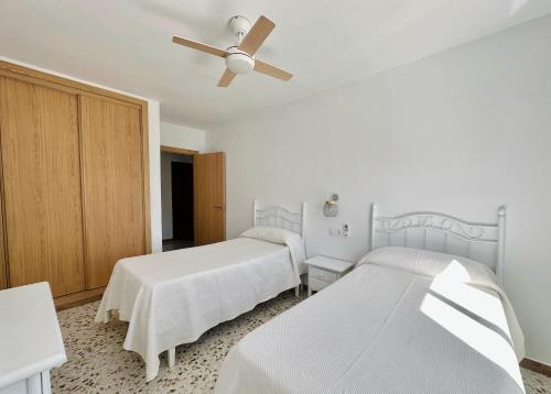 a bedroom with two beds and a ceiling fan at Apartamentos Turísticos Santo Rostro in Chipiona