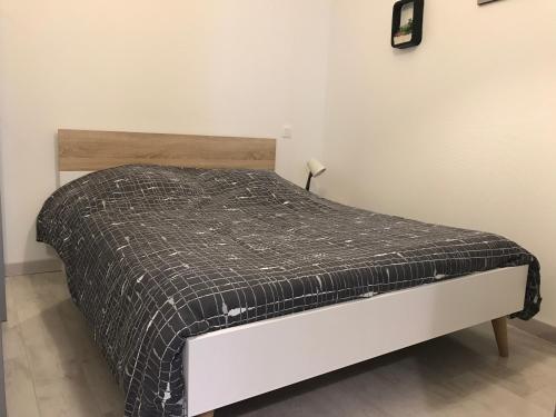 a bed with a black and white blanket on it at Le gite bleu in Ax-les-Thermes