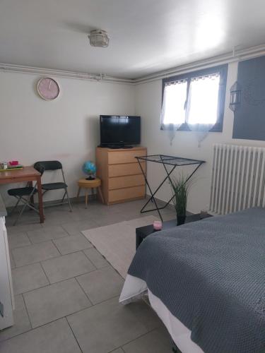 1 dormitorio con cama, mesa y TV en Studio 10 min aéroport orly, en Athis-Mons