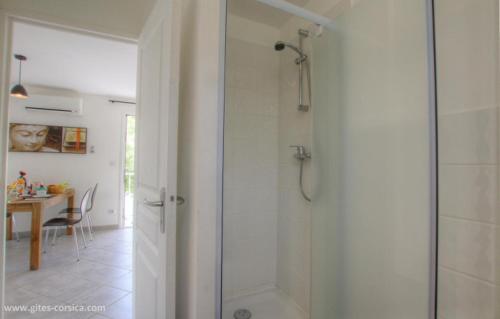 une salle de bain avec une douche avec une porte vitrée dans l'établissement Village Cargese 1, à Cargèse