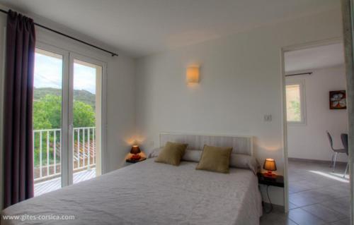 une chambre avec un grand lit et un balcon dans l'établissement Village Cargese 1, à Cargèse
