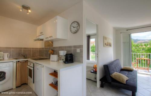 une cuisine avec un comptoir et une horloge au mur dans l'établissement Village Cargese 1, à Cargèse