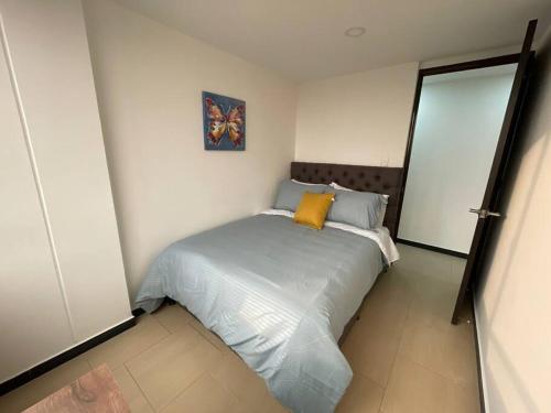 a bedroom with a bed with a yellow pillow on it at Encantador apartamento #3 cerca al aeropuerto in Bogotá