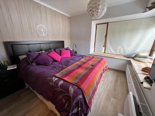 Un dormitorio con una gran cama púrpura con almohadas rosas en Departamento Valle Nevado Ski Resort Chile Ski in - Ski out, en Valle Nevado