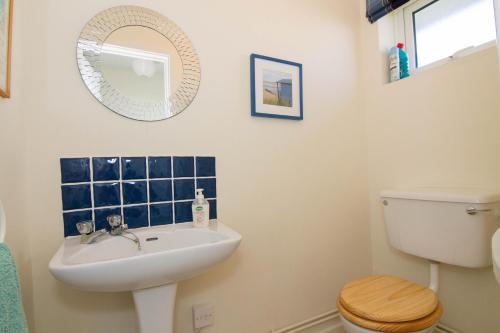 a bathroom with a sink and a toilet and a mirror at Sea Aster in Brancaster