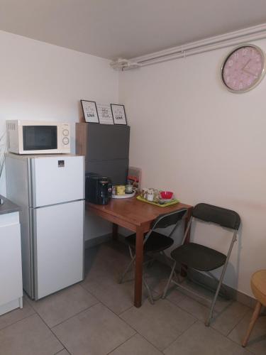 eine Küche mit einem Tisch, einer Mikrowelle und einem Kühlschrank in der Unterkunft Studio 10 min aéroport orly in Athis-Mons