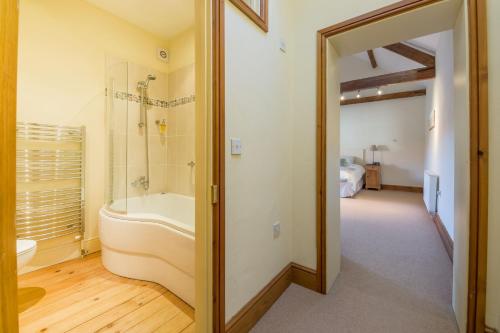 a bathroom with a tub and a shower and a sink at Geddings Farm Barn in Ringstead