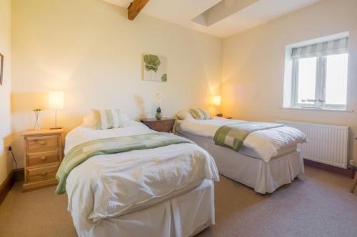 a bedroom with two beds and a window at Geddings Farm Barn in Ringstead