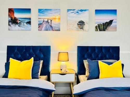 two beds with yellow and blue pillows in a room at Deluxe Apartment in Southend-On-Sea by Artisan Stays I Free Parking I Sleeps 5 in Southend-on-Sea
