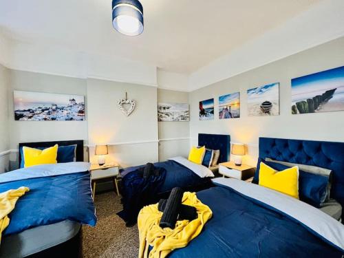 a bedroom with two beds with blue and yellow pillows at Beach Vibes in Southend-On-Sea by Artisan Stays I Leisure or Business I Free Parking I Sleeps 5 in Southend-on-Sea