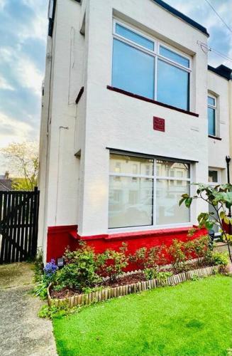 a white and red house with flowers in a yard at Deluxe Apartment in Southend-On-Sea by Artisan Stays I Free Parking I Sleeps 5 in Southend-on-Sea