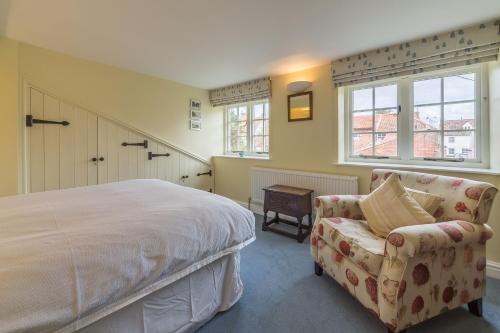 a bedroom with a bed and a chair and a window at 1 Honeymoon Row in Wells next the Sea