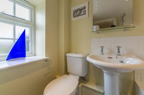 a bathroom with a toilet and a sink and a window at 1 Honeymoon Row in Wells next the Sea